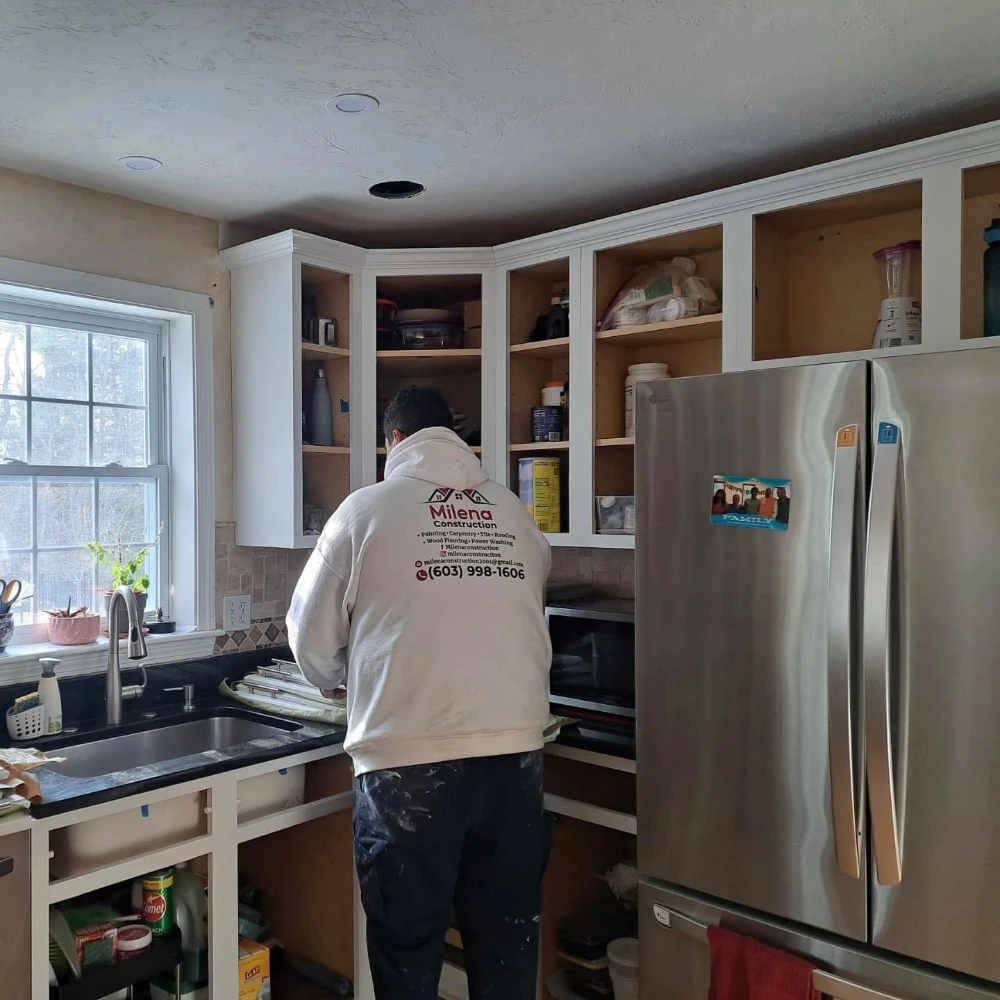 A Milena Construction team member painting cabinets on the job