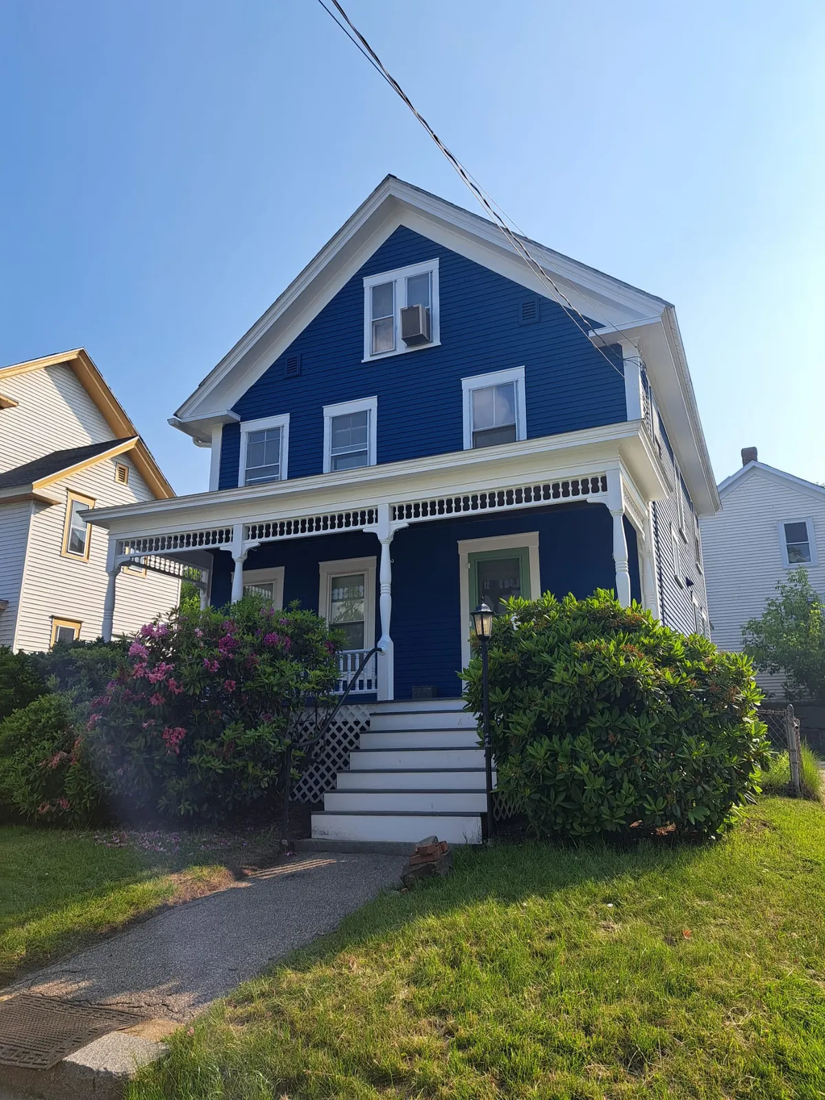 Blue New England home with white trim and a tidy front yard