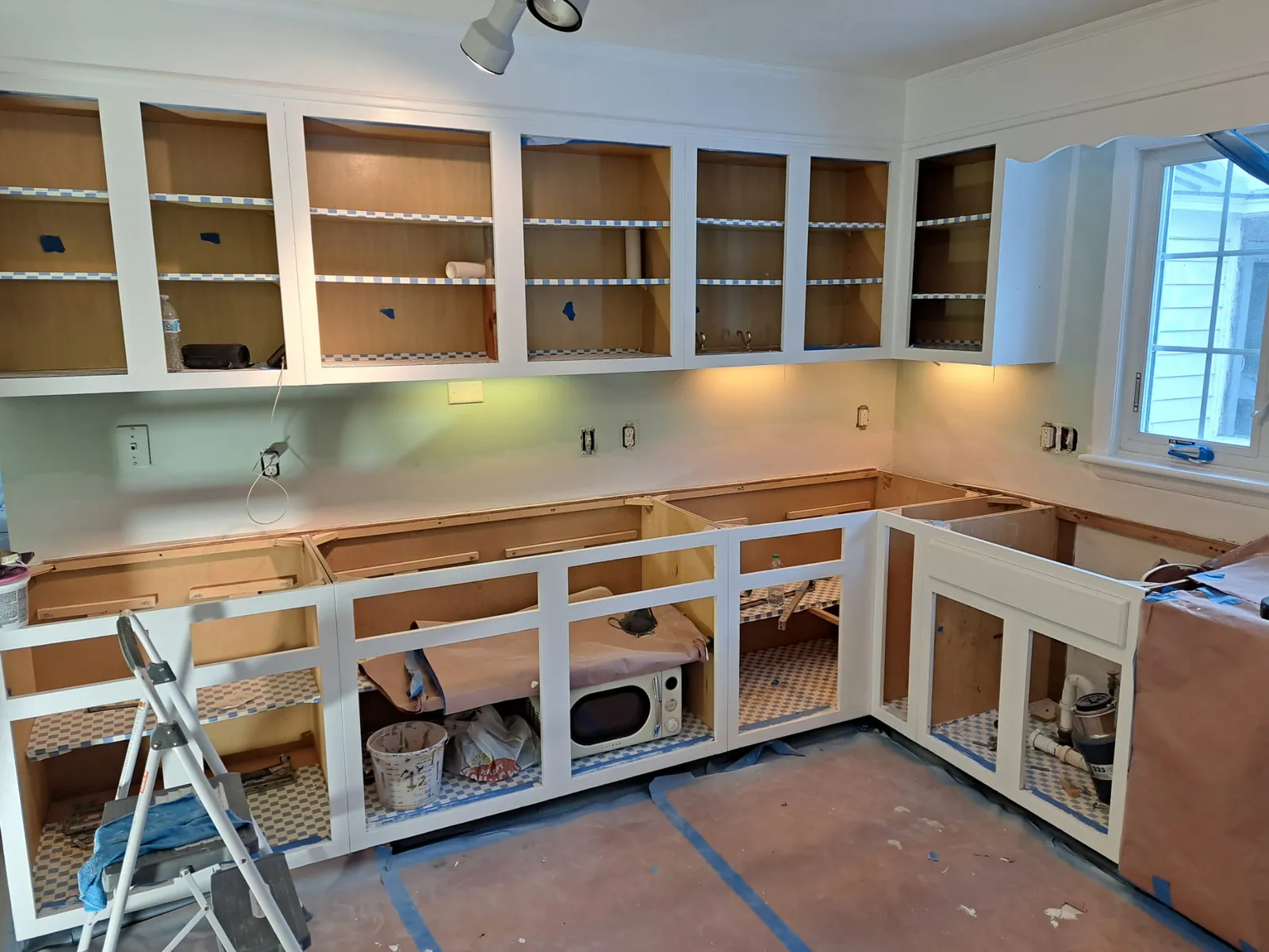 Built-in cabinetry being installed and painted near a staircase