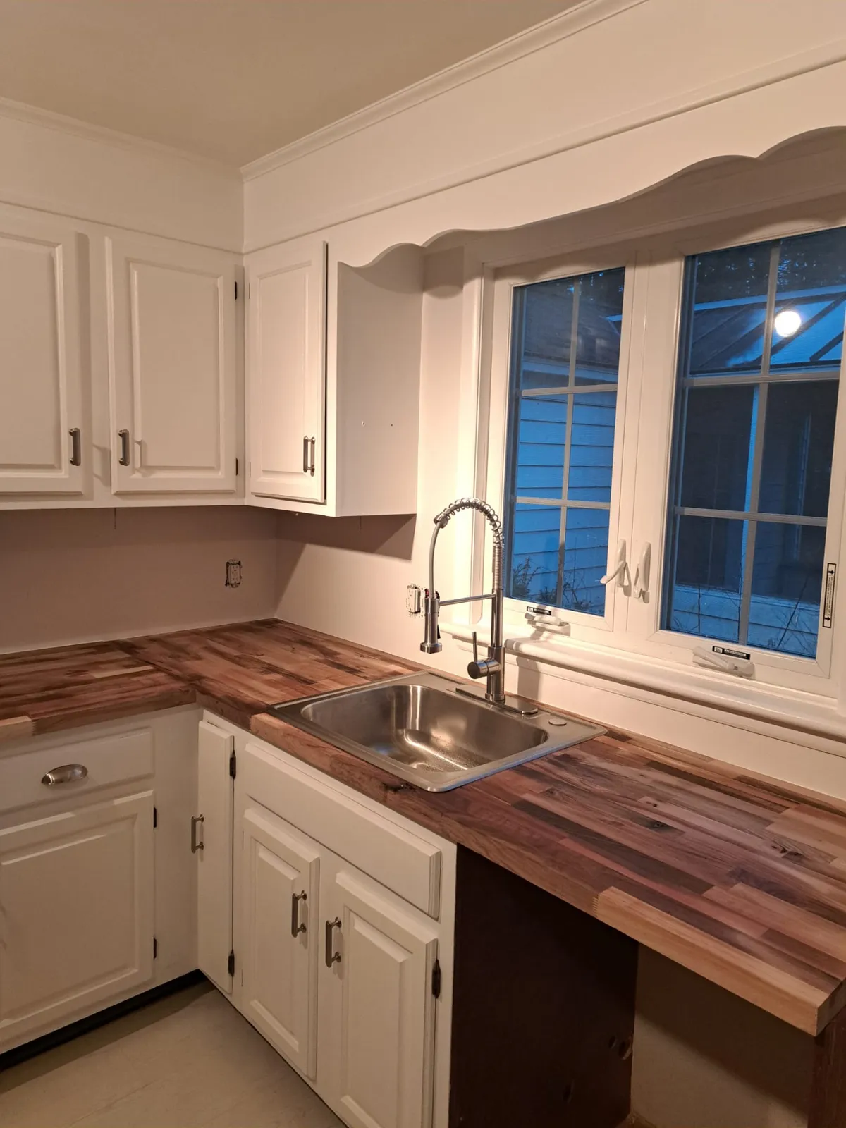 White kitchen with a farmhouse sink and butcher block under the windows