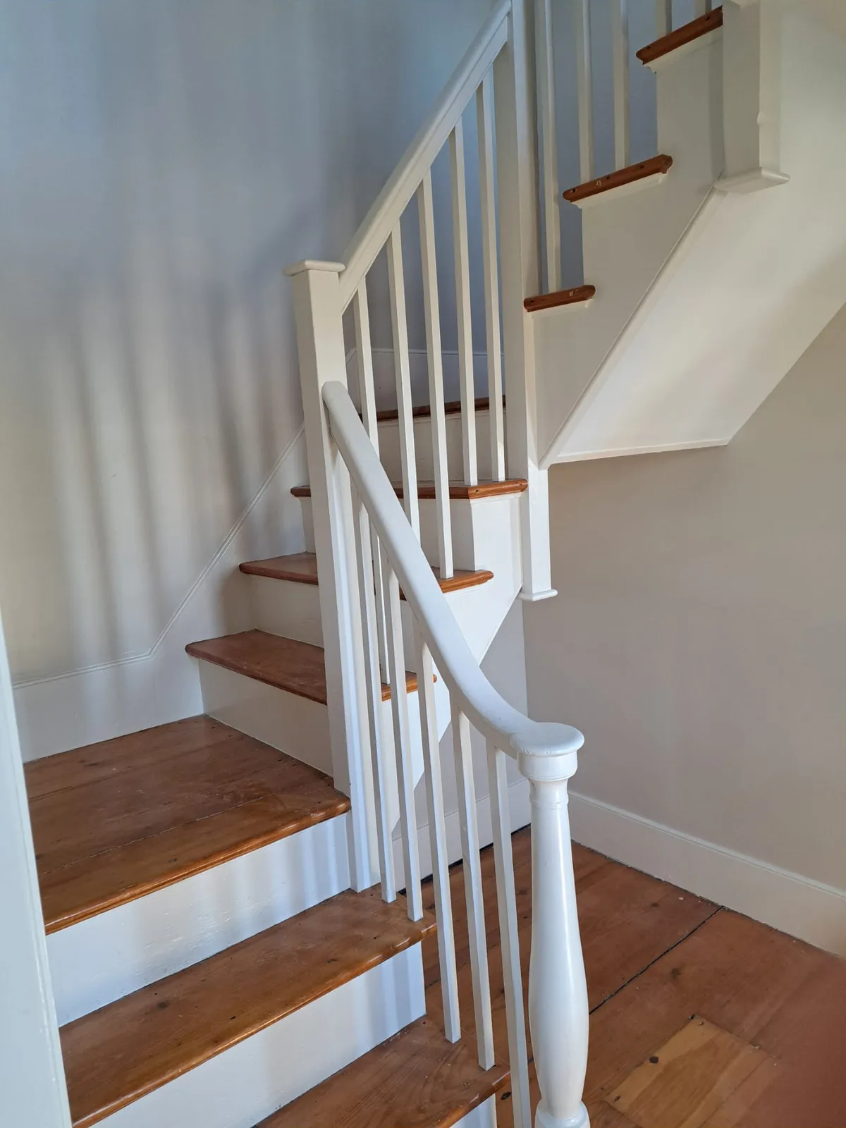 Restored wood staircase with fresh white railings
