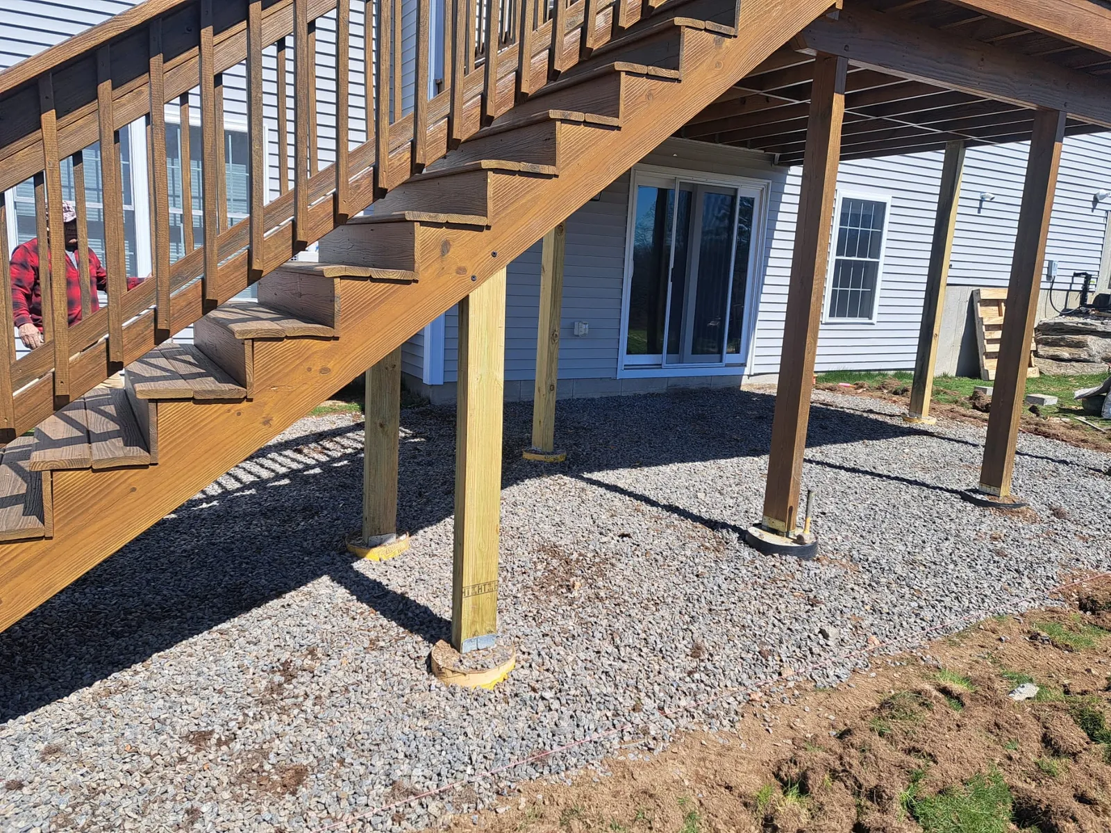 Newly built elevated deck with a staircase over a graveled yard
