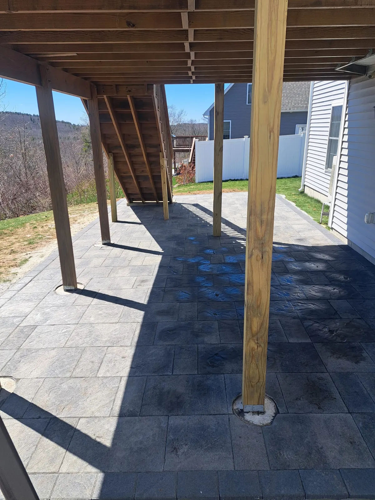 Paver patio and support posts beneath a deck