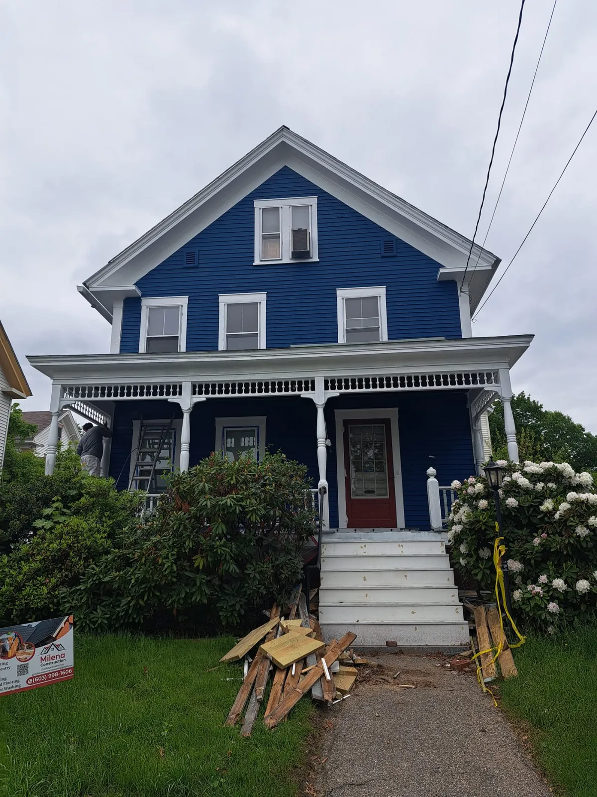 Blue Victorian home with white trim and a full front porch after an exterior repaint
