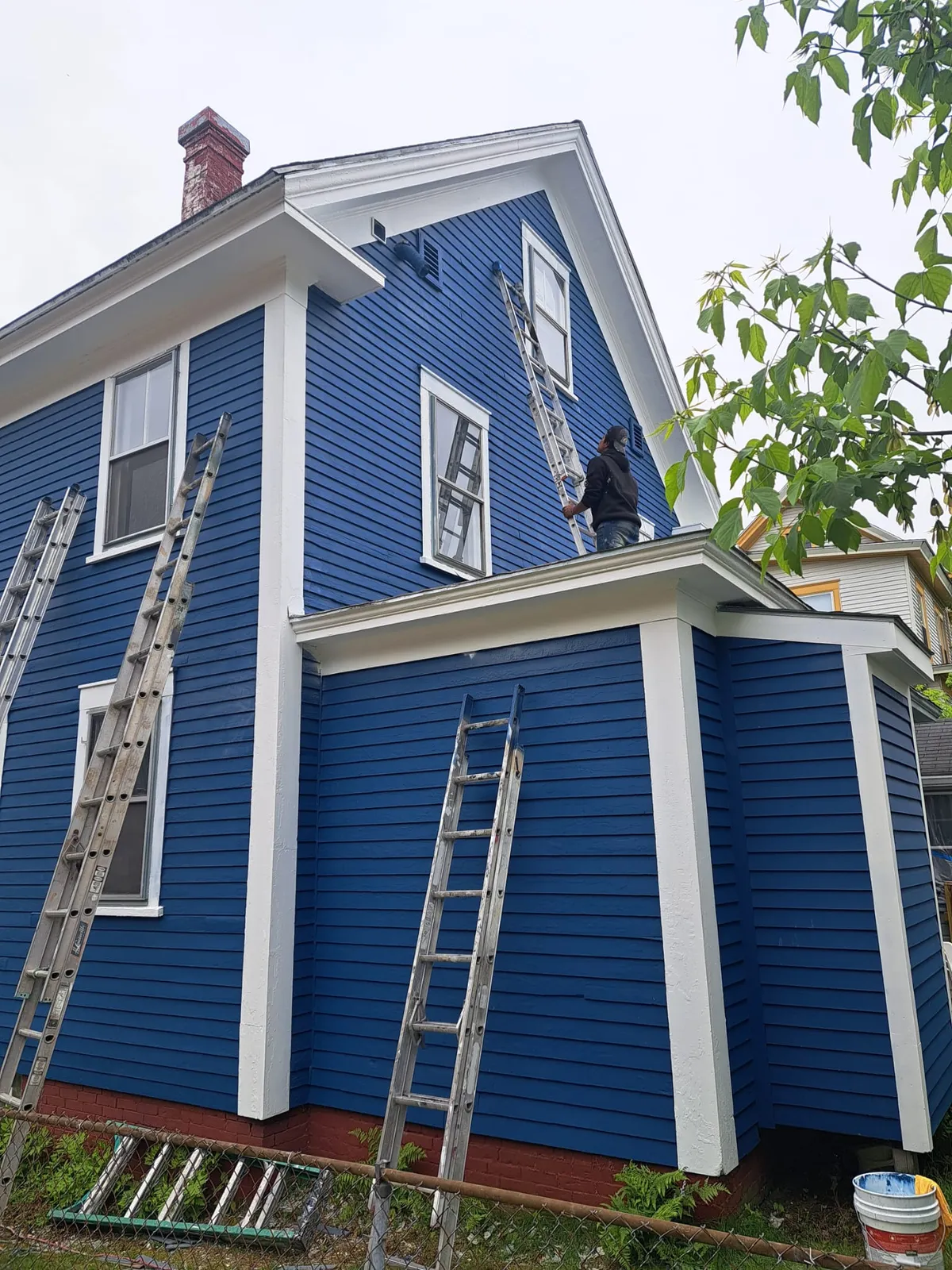 Exterior repaint in progress on a blue home