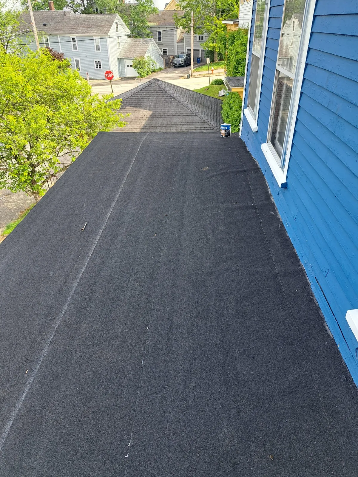 Fresh asphalt driveway beside a newly painted blue home