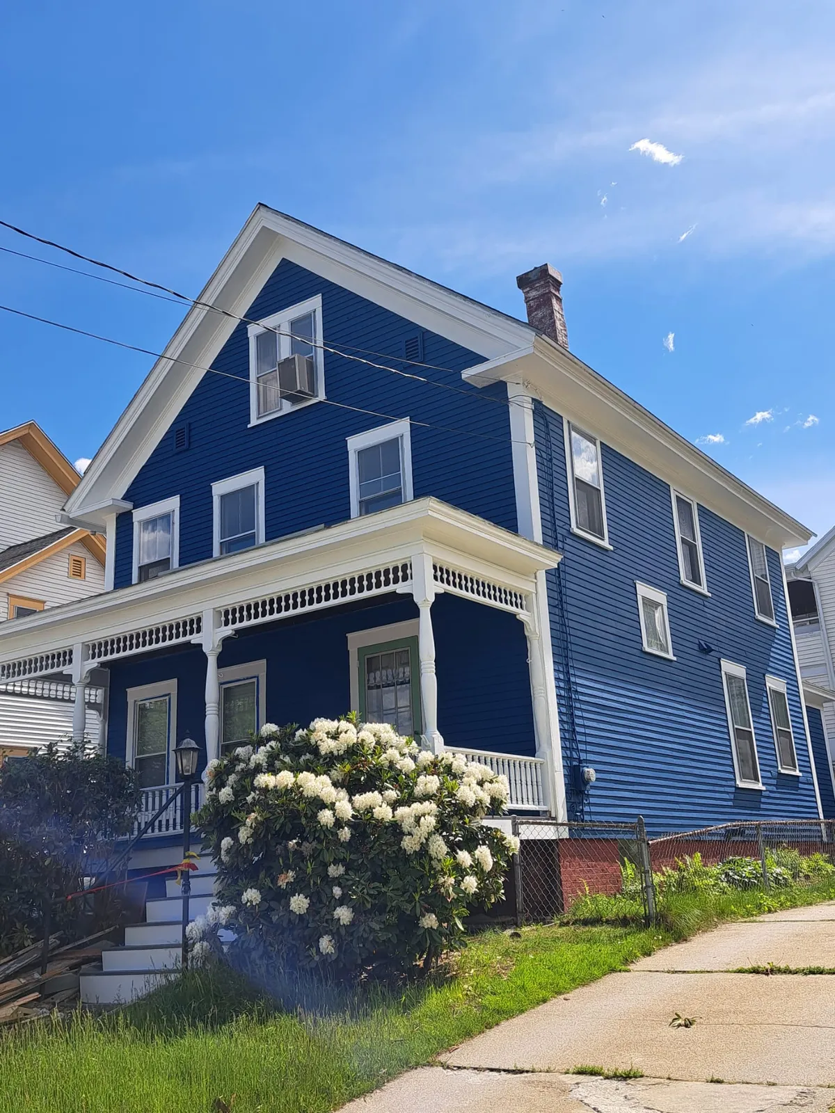 Blue New England colonial with fresh exterior paint, white trim and a blooming front yard