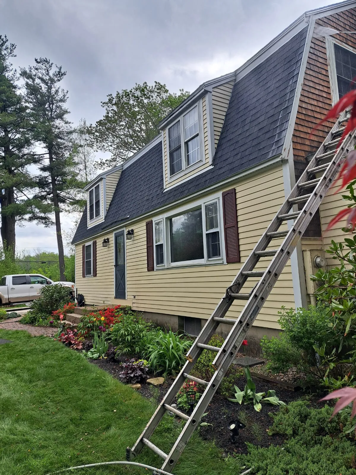 Exterior painting underway on a gambrel-roofed home