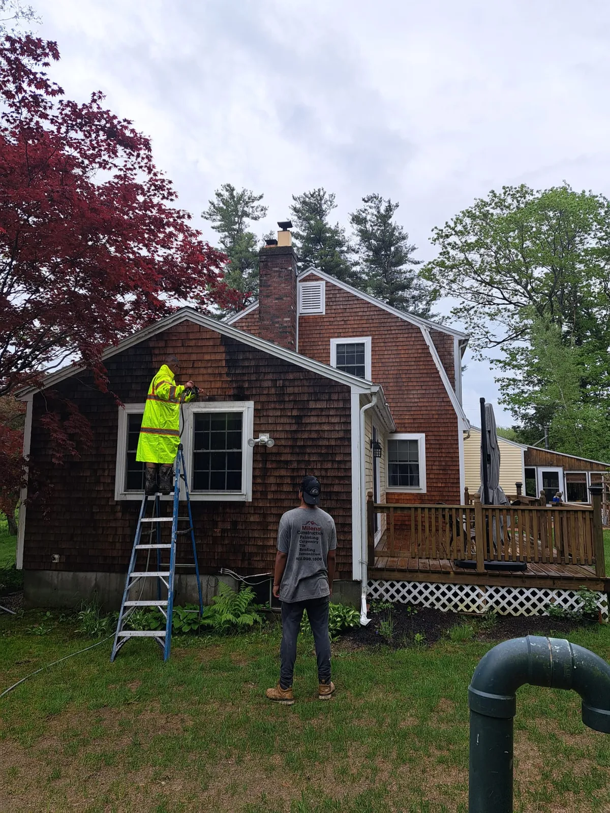 Crew member beside a cedar-shingled home